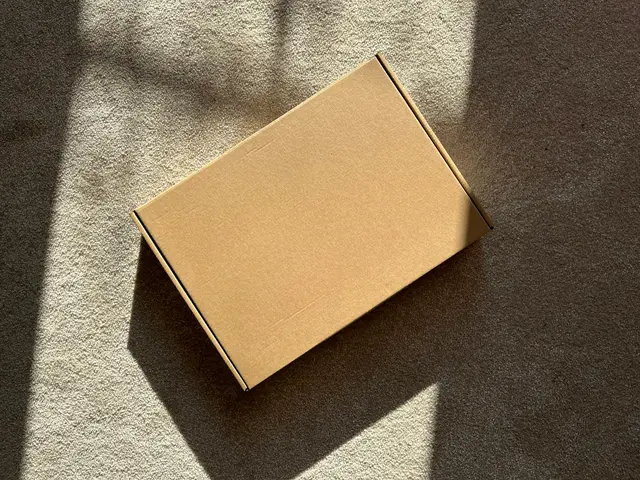 A closed cardboard box resting on a textured surface in soft light